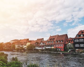 Houses by river against sky