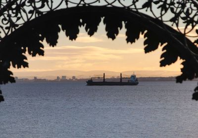 Scenic view of boat at sea against skyline framed by ornate metal arch in foreground 