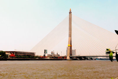 Bridge over sea by buildings against clear sky