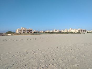 Buildings by sea against clear blue sky