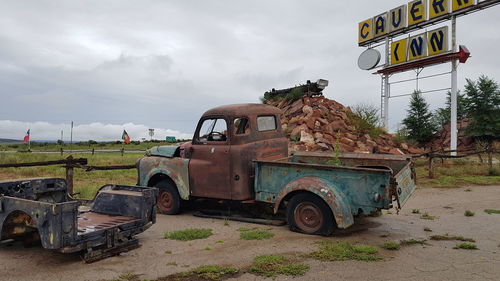 Abandoned car on field against sky