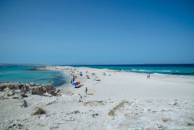 People at beach against clear sky