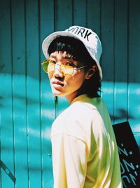 Close-up portrait of woman in sunglasses against wall