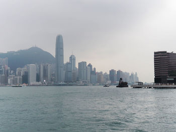 Sea by buildings in city against sky