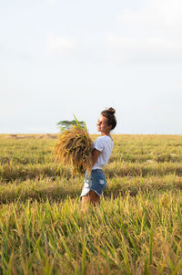 Rear view of woman standing on grassy field against sky