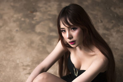 High angle portrait of beautiful young woman sitting on floor