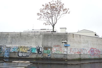 Graffiti on wall in city against clear sky