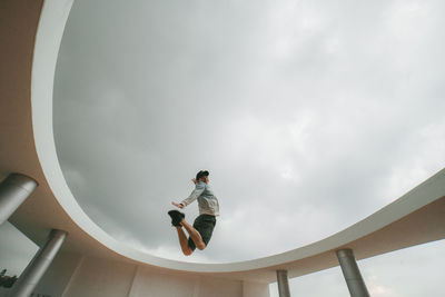 Low angle view portrait of man jumping against sky