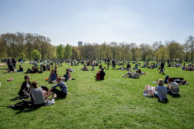 Crowd sitting at park on sunny day