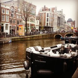 Boats moored in canal by buildings in city