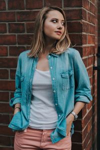 Beautiful young woman standing against wall