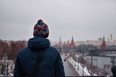 Rear view of man looking at city during winter