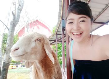 Portrait of happy young woman by goat