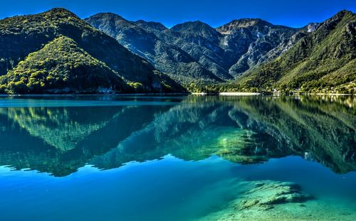 Scenic view of lake and mountains against blue sky