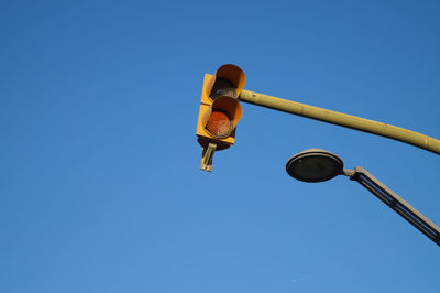 Low angle view of road signal against clear blue sky