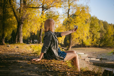 Young woman sitting on autumn leaves