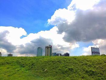 Scenic view of field and cityscape against sky