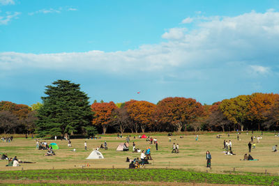 People on field against sky during autumn