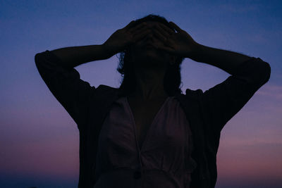 Silhouette woman with arms raised against sky during sunset