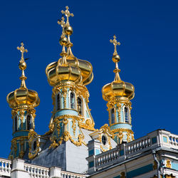 Low angle view of peterhof palace against clear blue sky in city