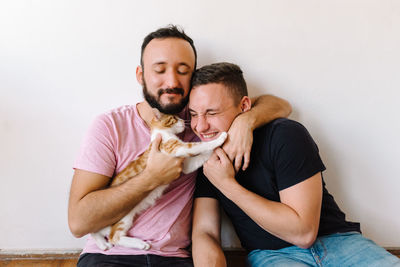 Gay couple playing with kitten.