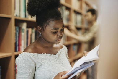 Female student reading book in library at university