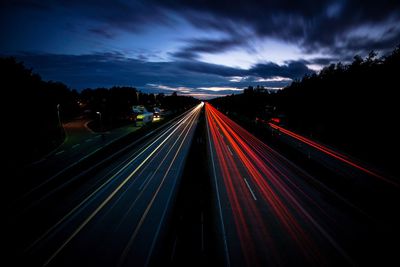 Light trails on road against sky at night