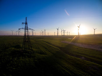 Windmills on field against sky during sunset