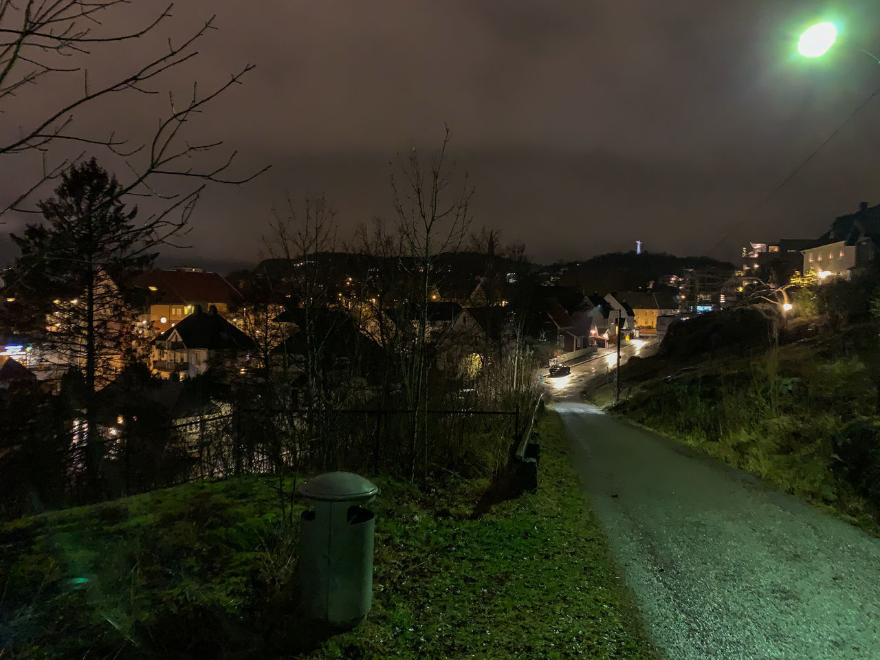 ILLUMINATED STREET BY BUILDINGS AGAINST SKY AT NIGHT