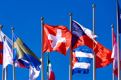 Low angle view of flags against clear blue sky