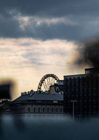 View of ferris wheel against cloudy sky