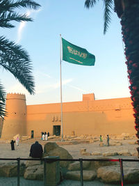 Information sign by palm trees and buildings in city against sky