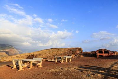 View of empty chairs on land against sky
