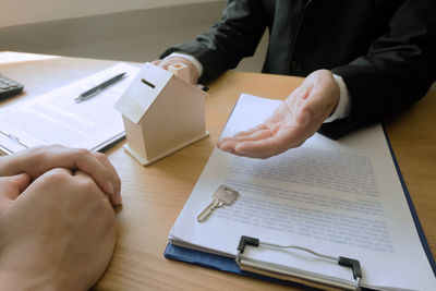 Midsection of man reading book on table