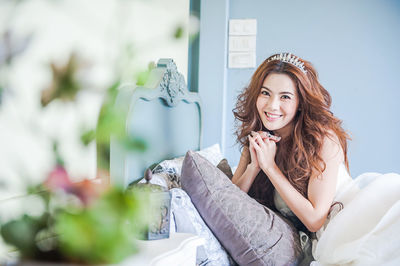 Portrait of smiling young woman on bed at home