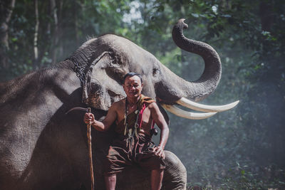 Man standing with elephant in forest