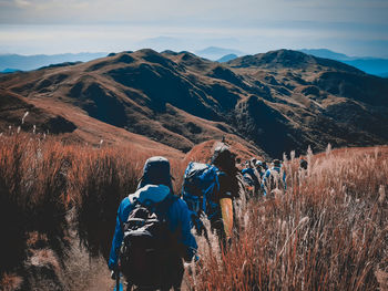 Rear view of people on field against mountain range