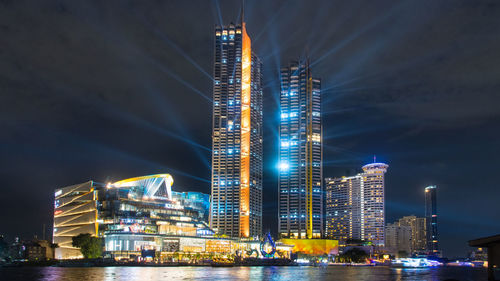 Illuminated buildings in city against sky at night