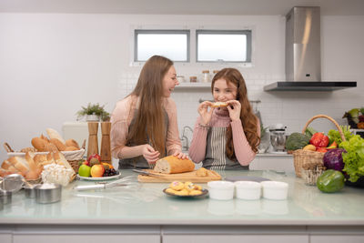 Mom and her younger kids daughter in a modern kitchen area celebrating joyous learning, baking, cake 