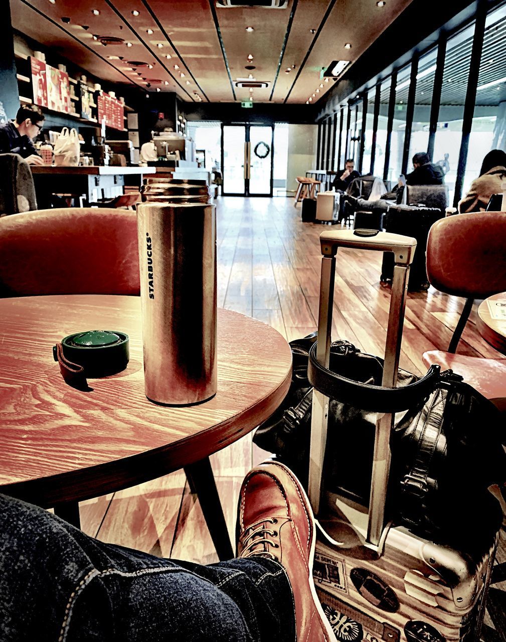 LOW SECTION OF PERSON SITTING ON CHAIR IN CAFE