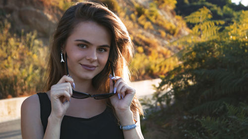 Portrait of smiling young woman wearing sunglasses while standing outdoors