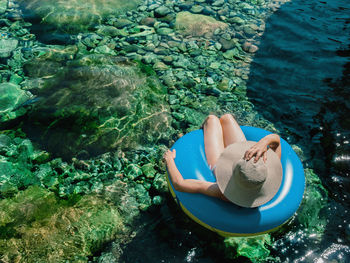 High angle view of woman sitting on inflatable ring in sea during sunny day