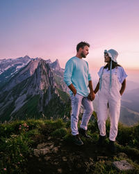 Men standing on mountain against sky during sunset