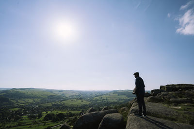 Hiker standing on rock at mountain against sky