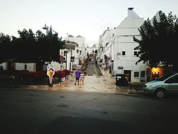 Cars on road by buildings in city against sky