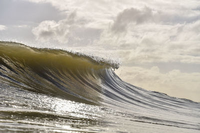 Sea waves splashing on shore against sky