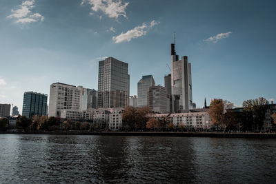 River by modern buildings against sky in city
