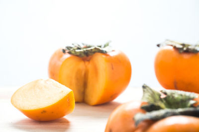 Close-up of persimmons on table against white background