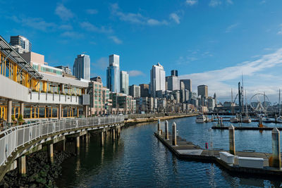 Bridge over river amidst buildings in city against sky