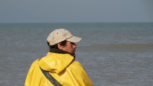 Rear view of man wearing cap against sea on sunny day
